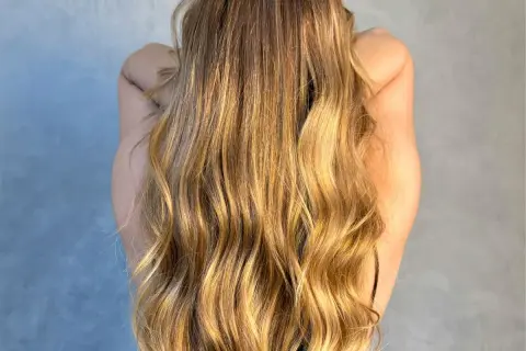 Długie, falowane blond włosy lśniące po olejowaniu na sucho.